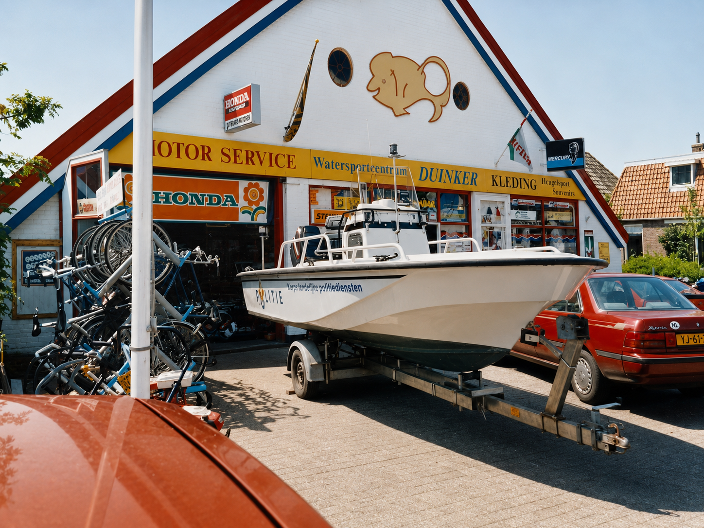 Duinker Motor Service shopfront — Mercury and Honda dealer in Oudeschild, Texel, with a Politie patrol boat on a trailer outside